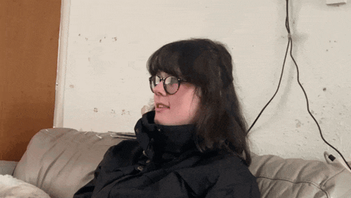 a woman wearing glasses sitting on a couch