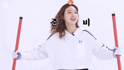 a woman in a white adidas hoodie is holding a red stick