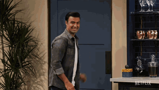 a man in a grey shirt is standing in front of a netflix advertisement