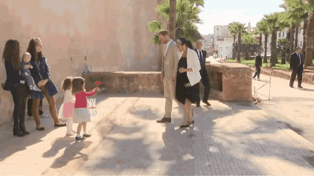 a group of people standing on a sidewalk including a little girl