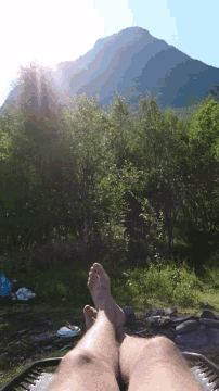 a person 's feet are visible in front of a mountain in the background