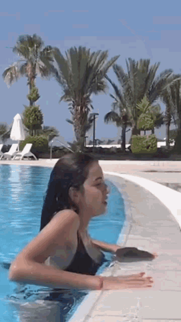 a woman in a black bikini is swimming in a swimming pool
