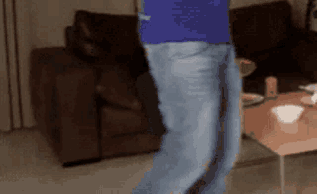 a blurry picture of a person standing in front of a brown couch