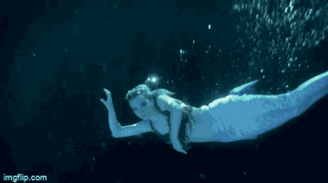 a woman in a mermaid costume is swimming in the ocean .