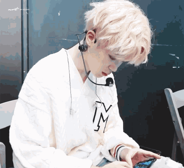 a person wearing a white sweater with the letter m on the front