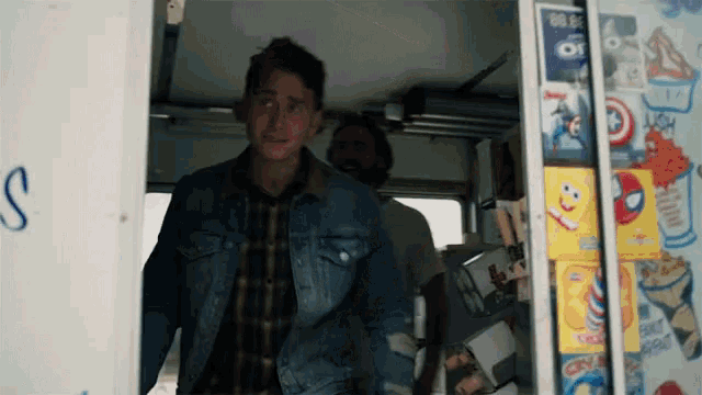 a man in a denim jacket stands in front of an ice cream truck with a box of oreos on it