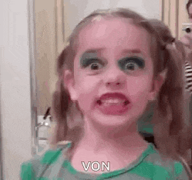 a little girl with a lot of makeup on her face .