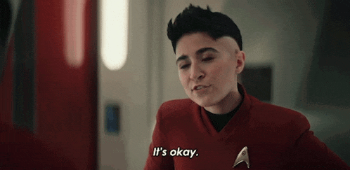 a woman with a shaved head is wearing a red jacket and says `` it 's okay '' .