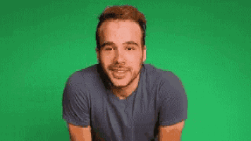 a man in a blue shirt is smiling and says hola muchachos ! on a green background .