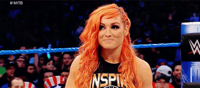 a woman with red hair is standing in a wrestling ring wearing a shirt that says nspin .