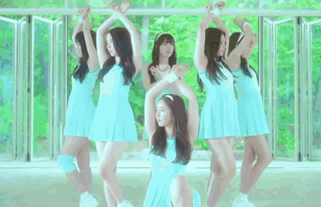 three women in blue dresses are holding hands in a line