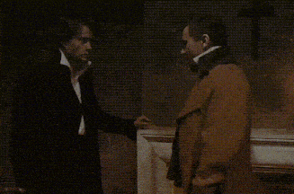 a man and a woman are standing next to each other and talking in a dark room .