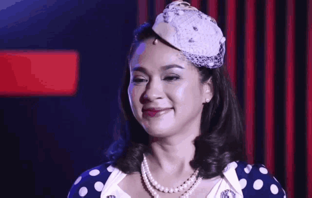 a woman wearing a polka dot dress and pearls is smiling .