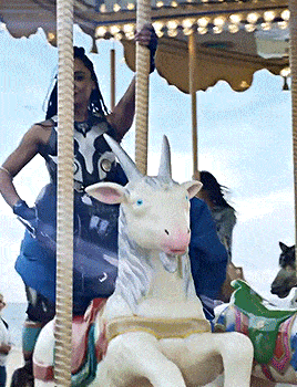 a woman is riding a merry go round with a unicorn statue