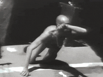 a black and white photo of a bald man crawling on the ground