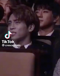 a man in a suit is sitting in a crowd of people and looking at something .