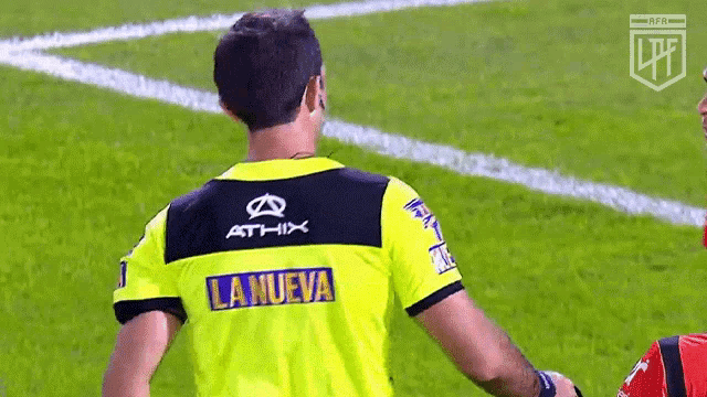 a referee wearing a yellow shirt with the word la nueva on it