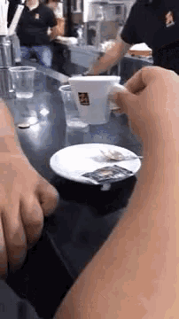 a person is sitting at a table with a cup of coffee and a saucer of sugar .