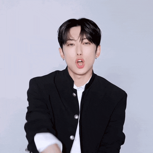 a young man wearing a black jacket and a white shirt with his mouth open