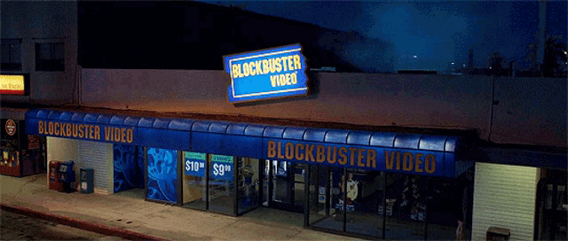 a blockbuster video store at night with a blue awning