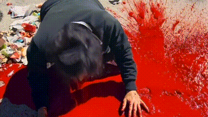 a person is kneeling in a pool of blood .