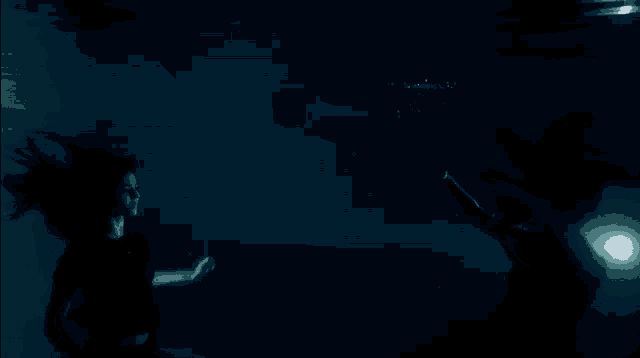 a man and a woman are swimming underwater in a dark pool