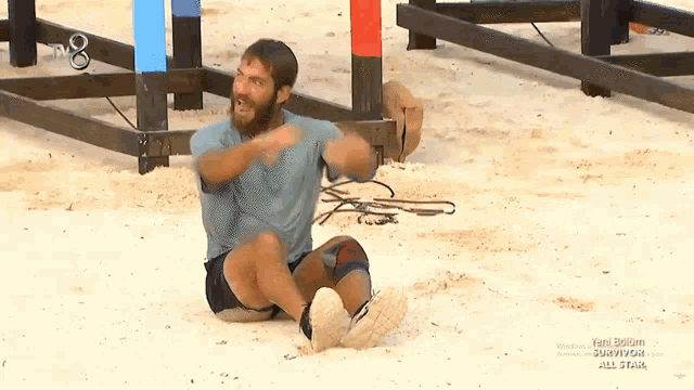 a man with a beard is sitting on the ground in front of a sign that says tb8