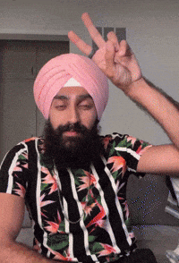 a man with a beard wearing a pink turban and a striped shirt is making a peace sign
