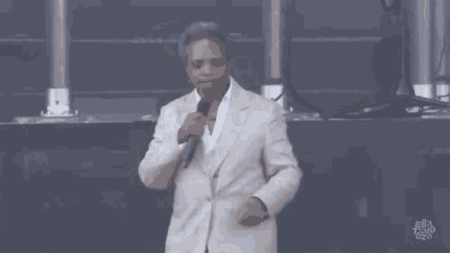 a man in a suit is standing on a stage holding a microphone and dancing .