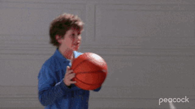 a boy in a blue shirt is throwing a red ball at a man in a suit who is holding a briefcase .