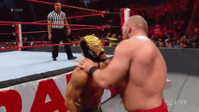 two men are wrestling in a ring with a referee in the background