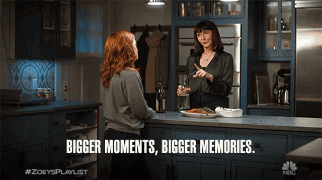 two women are talking in a kitchen with the words bigger moments bigger memories