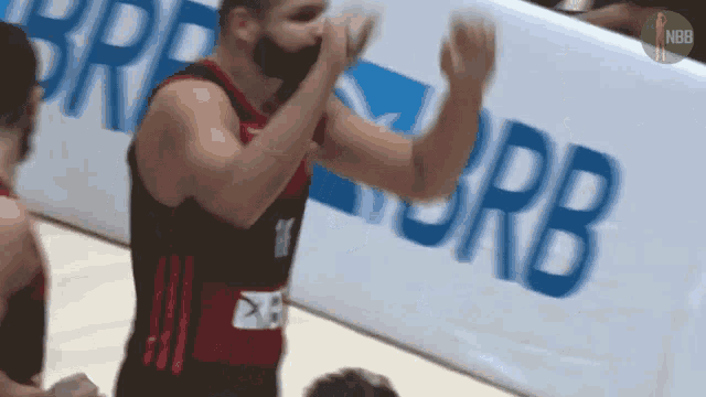 a basketball player is clapping his hands in front of a banner that says rb