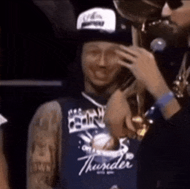 a man wearing a thunder jersey is holding a trophy .