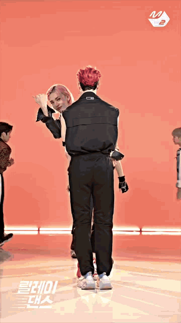 a man in a black jumpsuit is standing next to a woman in a pink shirt