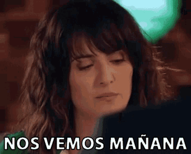 a woman is looking at her phone with the words nos vemos manana written on the bottom of her face .