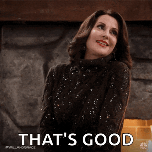 a woman in a sweater says that 's good in front of a fireplace