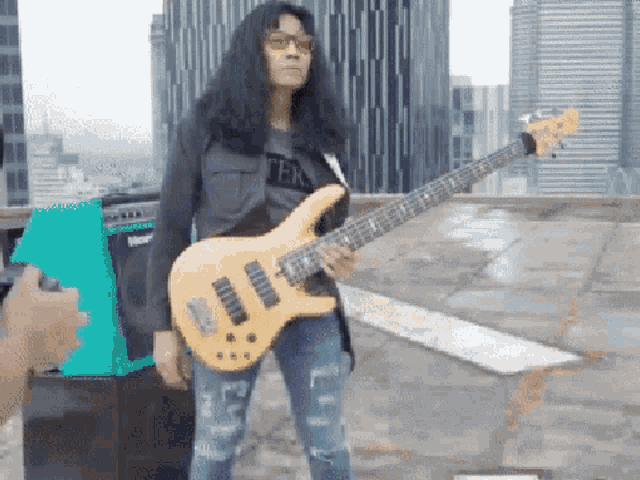a man with long hair is playing a guitar on top of a building