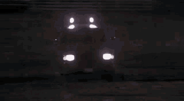 a truck is driving down a dirt road at night with the back door open .