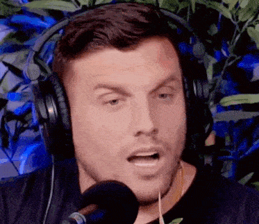 a man wearing headphones is talking into a microphone and making a funny face .