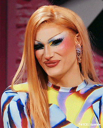 a close up of a drag queen 's face with a colorful dress and earrings .
