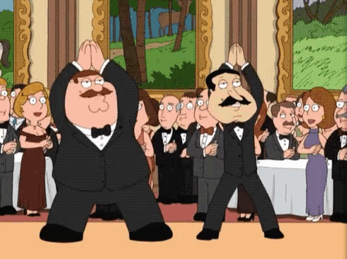 two men in tuxedos are dancing in front of a crowd .
