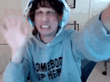 a woman wearing headphones and a hoodie is making a funny face .