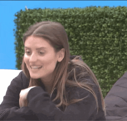 a woman in a black sweatshirt is smiling and laughing