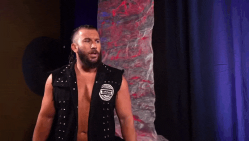 a man with a beard is wearing a black vest with studs on it .
