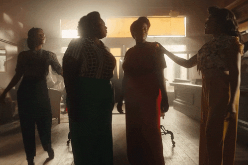 a group of women are standing in a room with their hands on each other 's shoulders