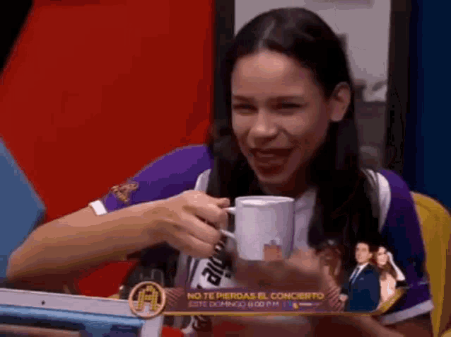 a woman in a purple shirt is holding a cup of coffee and smiling .