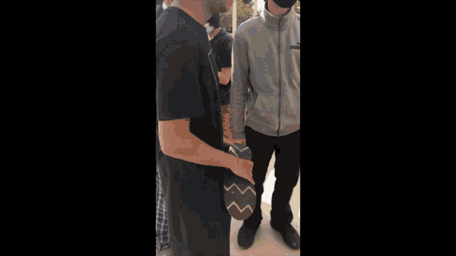 a man wearing a puma jacket talks to another man wearing a mask