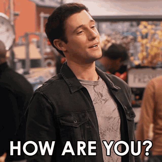 a man in a black jacket stands in a crowd and says how are you