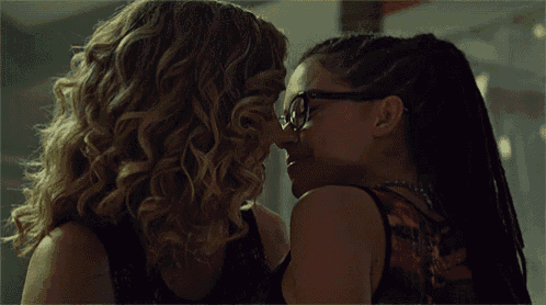 two women are kissing each other with one wearing glasses .